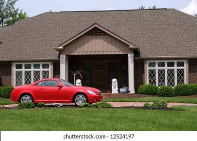 Red sports car in front of a brick suburban home in summer.