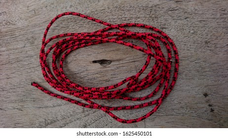 Red spotted black rope against a hollow old wooden background, heart-shaped rope structure