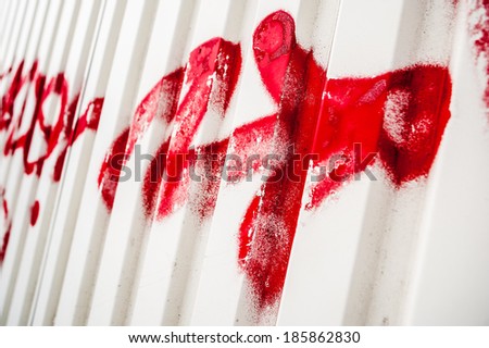 Red sprayed graffiti paint street art arrow sign on white metal wall surface