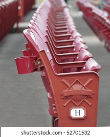 A Red Stadium Seat In Detail With Rows Of Seats Blurred Behind The Main Seat At A Baseball Stadium.