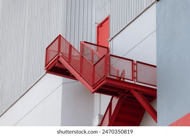 A red staircase with a white building in the background. fire escape ladder outside of building. - Powered by Shutterstock