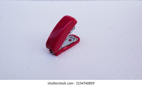 red stapler on a white background.
				