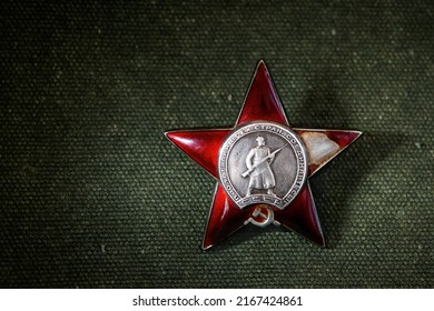 Red Star order on green uniform material background, Russia. Old Russian military medal to hero. High national Soviet army award in World War II. Concept of honor, patriotic and wwii victory symbol.
