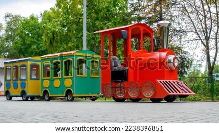 red steam locomotive with wagons, a children's attraction in an amusement park close-up against the background of green trees