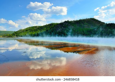 red steamy surface and reflection of the clouds in Midway Geyser Basin in Yellowstone National Park, Wyoming