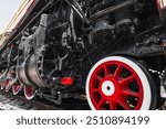 Red steel wheels of an old steam locomotive close-up. Retro steam locomotive on rails