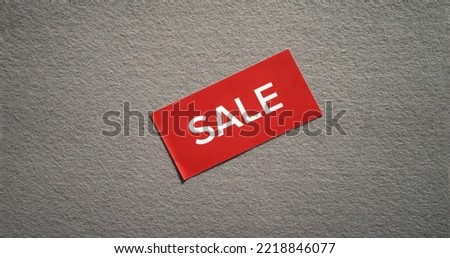 A red sticker with a white inscription sale on a gray felt fabric. Sale of felt material. Gray background with a sticker about the sale.
