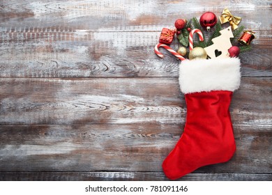 Red Stocking And Christmas Decorations On Wooden Table