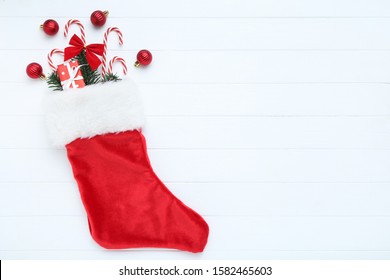 Red Stocking With Christmas Ornaments On White Wooden Table