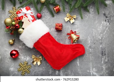 Red Stocking With Fir-tree Branches And Christmas Decorations On Wooden Table