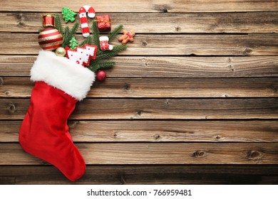 Red Stocking With Fir-tree Branches And Christmas Decorations On Wooden Table