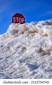 Red stop sign stopsign buried in deep snow drift in winter