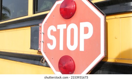 Red stop sign, yellow school bus in California, USA. Traffic warning on passenger schoolbus or shuttle in America. Public transportation safety on road. Caution or attention signage. Education concept