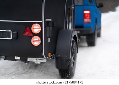 Red Stop Signal Lights On Camper Towed In The Winter Woods. Family Journey Time Together Away In The Forest Wild Life. Truck With RV Travel Trailer Driving Though Park. Family Journey Concept. 