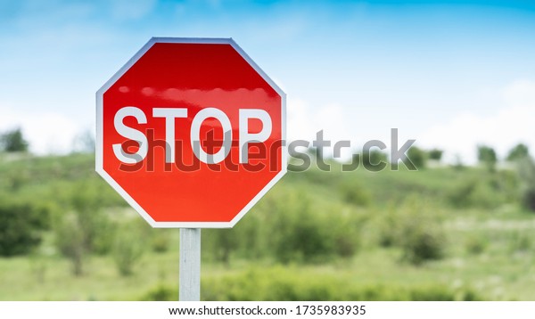 Red Stop Traffic Sign on Blue Sky Background and\
green field