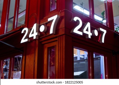 red store on the corner with a luminous sign 24/7, English style red store with glass windows, a night scene of building facade lighting details.