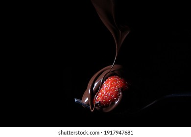 Red Strawberry On A Fork Covered With Chocolate On A Black Background, Creative Food Presentation