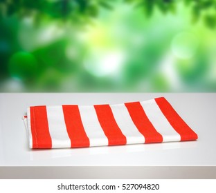 Red Stripe Folded Kitchen Towel On White Table Natural Blur Background.Empty Clean Cloth Cafe Food Decoration Concept.