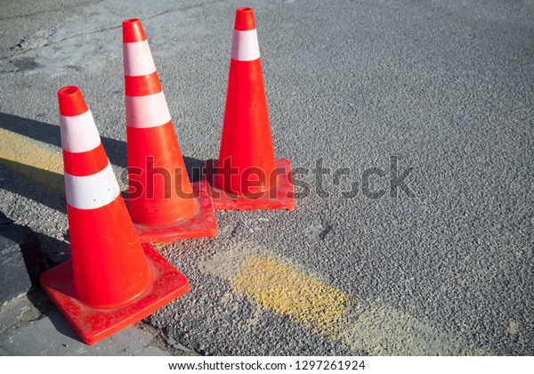 Red\
striped warning road cones stand on a\
roadside