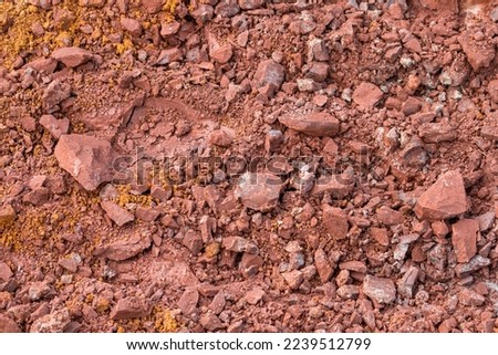 Red subsoil texture background. Dirt in nature. Red hard and compact soil at construction site. 
Subsoil layer. Geology. Underground earth. Sand stone rock. Geological sciences. Geological engineering