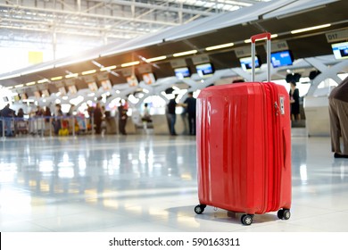 Red Suitcase In Airport Terminal.