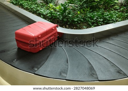Red Suitcase on Baggage Carousel with Copy Space. Bright red suitcase positioned on an airport baggage carousel with generous negative space beside it. Commercial travel concept suitable for tourism advertising, airline campaigns, vacation planning, luggage services, and transportation-related design.