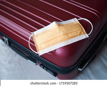 Red Suitcase On The Bed With Facial Mask On Top Ready To Travel