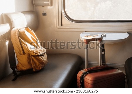 Red suitcase in the train. Backpack standing on couch of night sleeping train, Nobody. Empty wagon, cozy and comfortable travel, sunset light coming from the window.