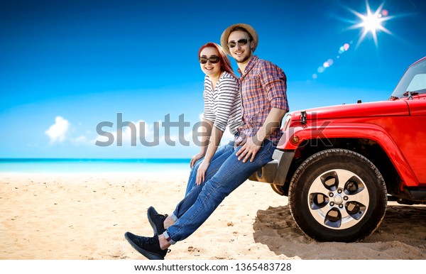 Red\
summer car on beach and two lovers. Young two people and free space\
for your decoration. Blue sky with sun and clouds.\
