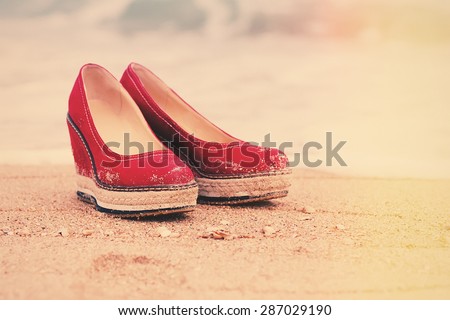 red summer shoes standing on tropical sandy ocean beach. vintage picture