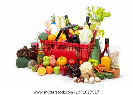 Red supermarket shopping basket full of  fresh organic colorful foods and groceries with assorted ingredients on white background