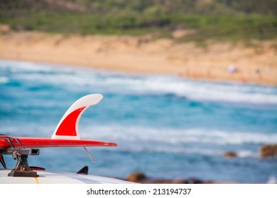 Red Surfboard On A Car Roof By The Shore