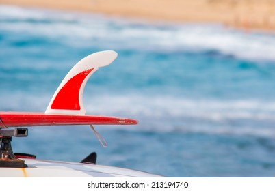 Red Surfboard On A Car Roof By The Shore