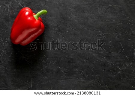 Red sweet Bulgarian pepper one whole on dark background, top view, space to copy text.