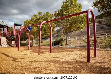 Red Swing Set On Playground With Wood Chips