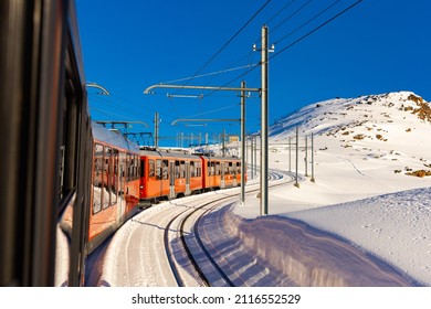 Red Swiss Train Running Through The Snow