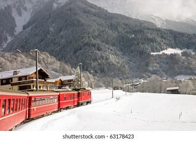 A Red Swiss Train Running Through The Snow.