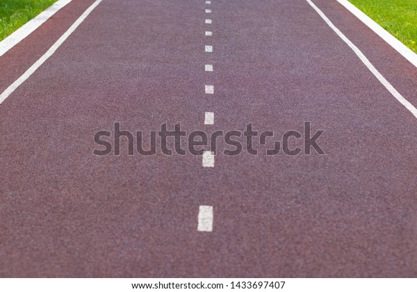 Red synthetic racetrack\
or cycle track with white markings, look right in the middle.\
Selective focus.