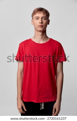 Red t shirt worn by a standing youth in a studio setting, casual fashion with a relaxed pose, front view and clean background, everyday wardrobe concept