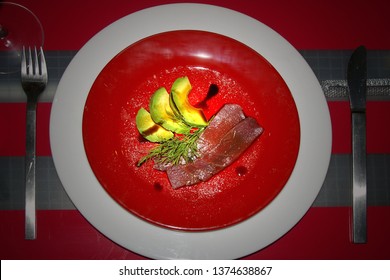 Red Table Set With A Plate Of Homemade Ahi Tuna Carpaccio With Avocado Slices