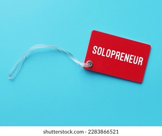 Red tag card on blue background with text written SOLOPRENEUR, person who sets up and runs business on their own, works independently and doesn't hire employees