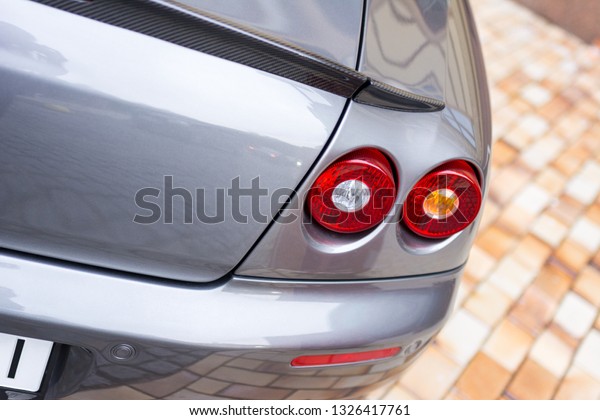 Red tail lights (rear lights, brake lights) of\
grey car close up image.