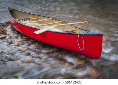 Red Tandem Canoe With A Paddle On A Shallow Rocky River