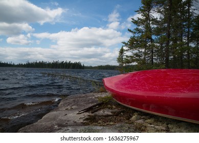 Red Tandem Canoe Upside Down On A Rocky Shore