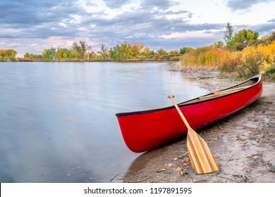 Red Tandem Canoe With A Wooden Paddle On A Lake Shore, Fall Scenery