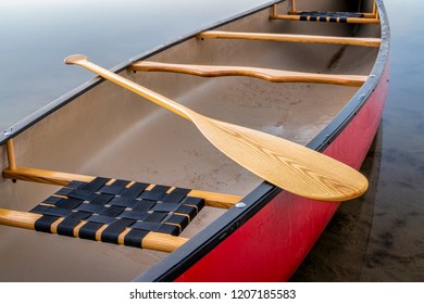 Red Tandem Canoe With A Wooden Paddle On A Calm Lake