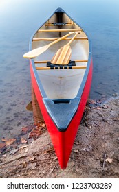 Red Tandem Canoe With  Wooden Paddles On A Lake Shore