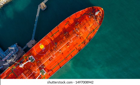 Red tanker ship loading and unloading oil and gas storage at industrial dock port, Business import export petrol and chemical by tanker ship transportation, Loading arm oil and gas offshore platforms.