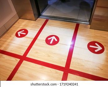 Red Tape On The Elevator Or Lift Floor With Arrow Sign For Direction Of Standing Position To Limit Or Control Number Of People Entry Into The Lift ,Social Distancing In COVID-19 Or Coronavirus Crisis