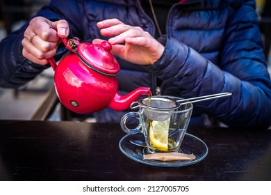 A Red Tea Pot Held In The Hands, Close-up